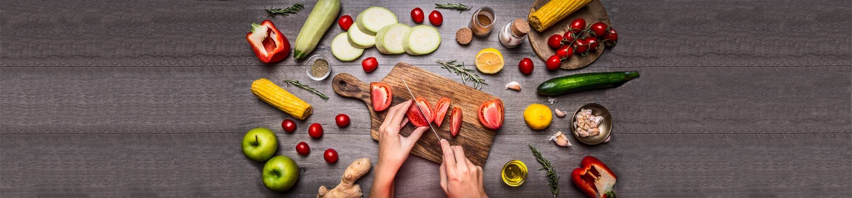 image of hands cutting up fruit and vegetables on cutting board